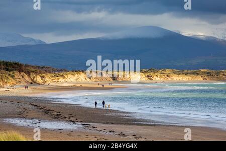 Newborough beach and sand dunes with the snow covered Snowdonia mountains in the background, Anglesey Stock Photo