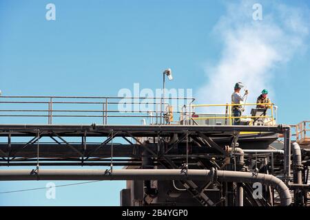 Two workers consult about a welding job at a modern factory. Stock Photo
