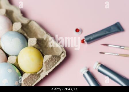 The concept of coloring Easter eggs in pastel watercolor colors. Paints and brushes for coloring eggs for Easter on pink background. Stock Photo