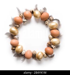 Easter creative modern wreath of golden, quail, chicken eggs, feather isolated on white background. View from above. Space for text. Stock Photo