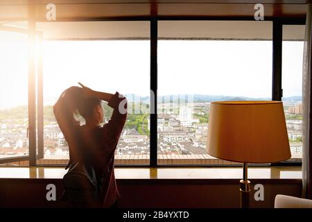 Woman tight hair ready while looking at view from window Stock Photo