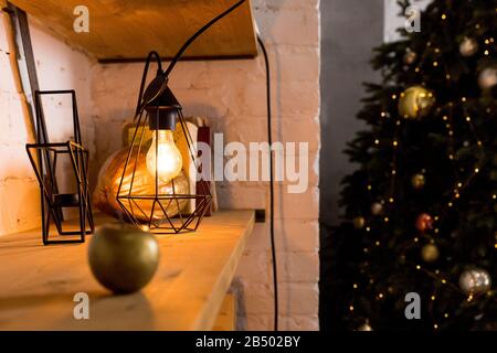 Bulbs hanging on steel structure.Edison lamps in a metallic geometric lampshade on blurred christmas tree background. Selective focus. Toned image Stock Photo