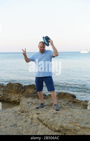 young man in hat and shorts posing on the seashore Stock Photo