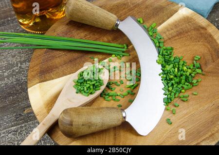 https://l450v.alamy.com/450v/2b50cjy/preparation-of-herbs-for-meal-isolated-brown-wood-cutting-board-with-chefs-mincing-knife-chopped-green-chives-and-wooden-spoon-2b50cjy.jpg