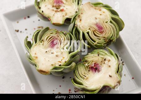 Green artichoke halves in white plate Stock Photo