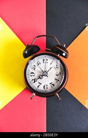 Yellow alarm clock on multicolored background Stock Photo - Alamy