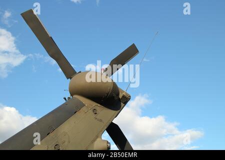 tail boom and rotor with rear propeller blades on back of military helicopter against blue sky background Stock Photo