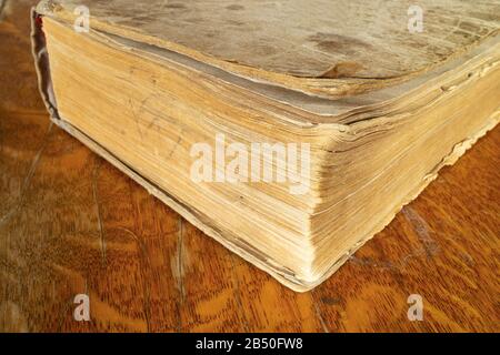 Aging book rests upon wooden table.Type from the side locked book Stock Photo