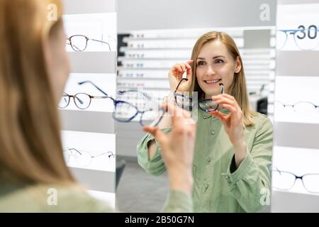 woman trying on optical glasses in eyewear store Stock Photo