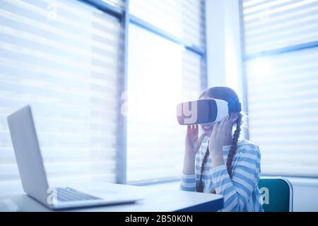 Horizontal medium portrait of unrecognizable eleven-year-old Caucasian girl using VR headset smiling, copy space Stock Photo
