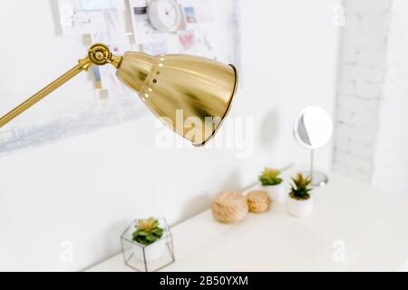 golden Lamp ,table lamp, paperwork and stationery items on white table.Bright Scandinavian home office desk table workspace with laptop, lamp, books Stock Photo