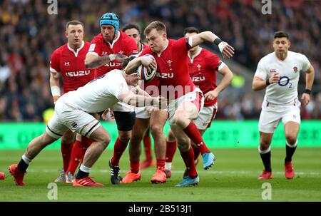 Wales' Nick Tompkins (centre) is tackled by England's Tom Curry (left) during the Guinness Six Nations match at Twickenham Stadium, London. Stock Photo