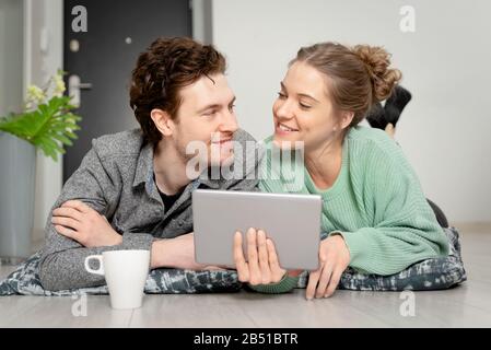 Happy couple with tablet shopping online. Two person lying on the floor, lifestyle concept Stock Photo