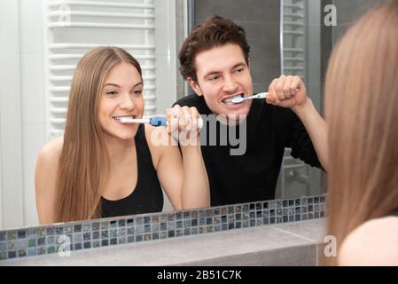 Couple brushing teeth in bathroom. Dental health concept Stock Photo