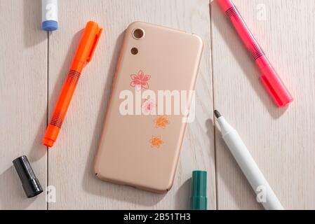 Flowers drawn on beige phone case, top view Stock Photo