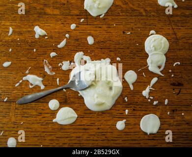 Metal Spoon In Yogurt Splatters Stock Photo