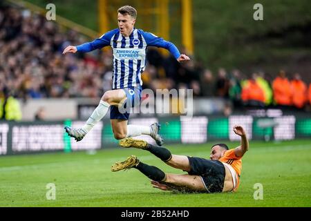 Wolverhampton, UK. 7th March 2020English Premier League, Wolverhampton Wanderers versus Brighton and Hove Albion; Romain Sa&#xef;ss of Wolverhampton Wanderers clears the ball as Solly March of Brighton &amp; Hove Albion hurdles the challenge - Strictly Editorial Use Only. No use with unauthorized audio, video, data, fixture lists, club/league logos or 'live' services. Online in-match use limited to 120 images, no video emulation. No use in betting, games or single club/league/player publications Credit: Action Plus Sports Images/Alamy Live News Stock Photo