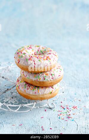 three donuts on a blue background with colorful sugar sprinkles Stock ...