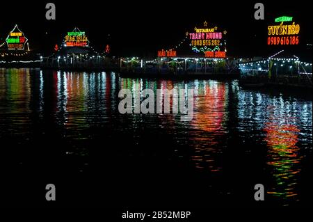 Cat Ba island, Vietnam Oct 17, 2019. Restaurants on the water at night. pockmarked color reflection on black water Stock Photo