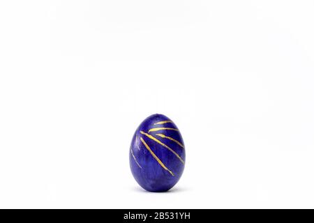 Happy Easter. One easter egg trendy colored classic blue, white and golden on white background. Copy space. Minimal style. Stock Photo
