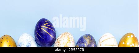 Easter banner. trendy colored easter eggs classic blue, white and golden on blue. Minimal style, top view, flatlay, copy space. Stock Photo