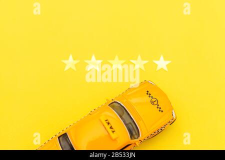 Yellow toy car Taxi Cab and 5 stars rating isolated on yellow background. Smartphone application of taxi service for online searching calling and book Stock Photo