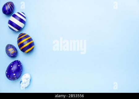 Happy Easter. Frame for text made of easter eggs trendy colored classic blue, white and golden on blue. Minimal style, top view, flatlay, copy space. Stock Photo