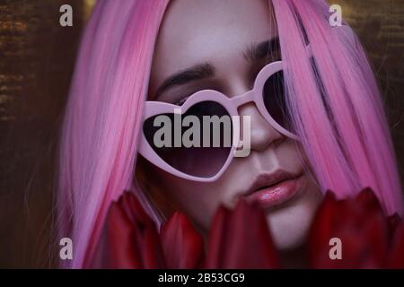 Woman with red tulip flowers - Pink hair and heart-shaped glasses Stock Photo