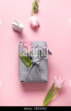 Spring eco-friendly gift wrapped in grey textile with tulip flowers decor on pink. Sustainable gift. Zero waste. Easter holiday. Traditional Japanese Stock Photo