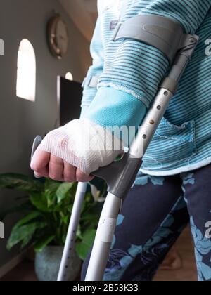 Injured woman trying to walk on Crutches at home Stock Photo