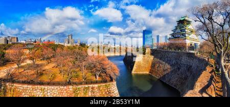 Rainbow over Osaka city in Japan with local garden, historic park surrounded by stone walls, water moat and traditional tower. Stock Photo