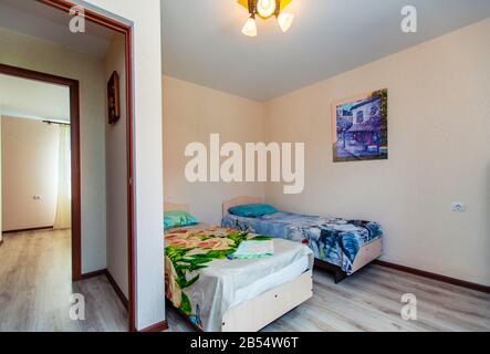A small room in the guest house with two single beds with a green and blue bedspread.. Stock Photo