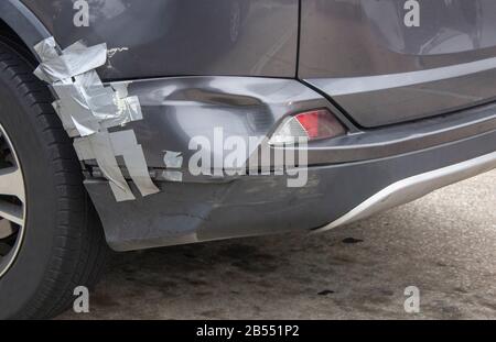 a gray car with a dented rear bumper that is held together with duct tape Stock Photo