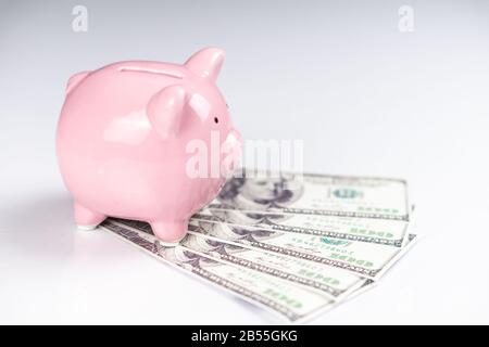 Piggy bank with US one hundred dollar bills Stock Photo