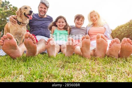 Happy family doing picnic in nature park outdoor - Father, mother, son and daughter having fun together with their pet on sunny day - Travel, parentho Stock Photo