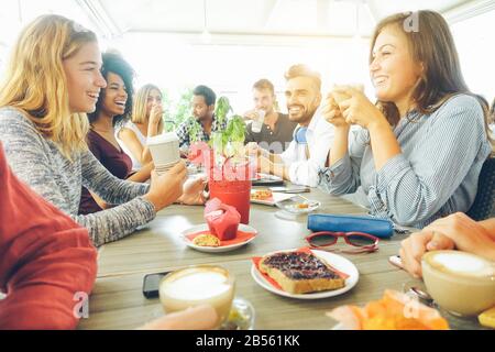 Happy friends having coffee break at bar cafe - Young hipster people enjoying breakfast - Friendship and good mood concept - Focus on right woman drin Stock Photo