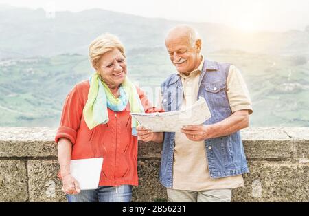 Senior couple reading tourist map inside italian castle outdoor - Mature Husband and wife having fun in romantic vacation- Love and joyful elderly lif Stock Photo