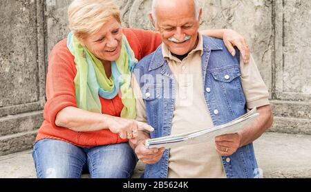 Senior couple reading tourist map inside italian castle outdoor - Mature Husband and wife having fun in romantic vacation- Love and joyful elderly lif Stock Photo