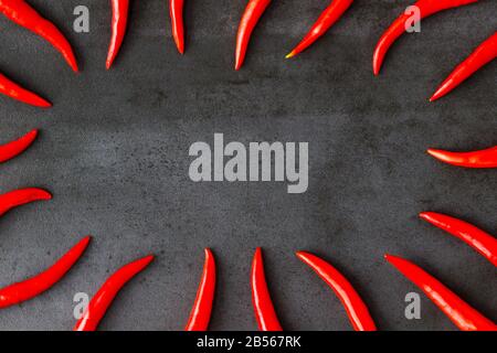 Flat lay of Thai red fresh hot chilli peppers on black stone background. Food pattern. Popular spices.  Banner. Free space for text Stock Photo