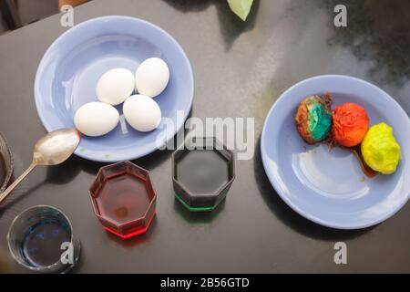 glasses with multicolored coloring water ant paints. close-up. Easter preparations. Multicolored Eggs in blue plate. Stock Photo