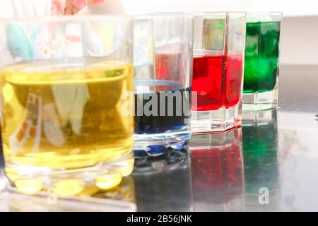glasses with multicolored coloring water, close-up. Easter preparations. Stock Photo