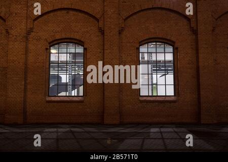 Facade of a vintage old red brick warehouse, used from an Industrial Revolution Era facotry plant, with large windows, showing a renovated and reconst Stock Photo