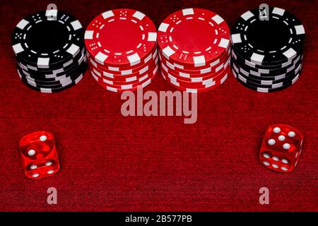 a close up of an rolled 5 and 2 on a pair of casino style dice with stacks of red and black clay chips on a red felt table.  Shot for centered Space f Stock Photo