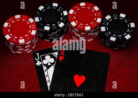 A close up of Blackjack hand with unique black, white and red cards with Black and Red Clay poker chips on a Dark Red Felt table surface.  Room for Co Stock Photo