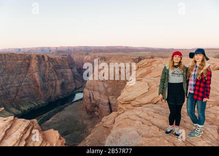 girls on Horseshoe Bend in Glen Canyon National Recreation Area in early dawn Stock Photo
