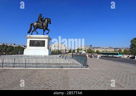 Pedestrians by a bronze statue of Henry IV on Pont Neuf towards the right bank of the Seine. Stock Photo