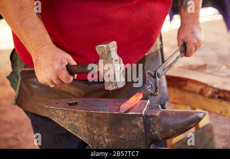 Blacksmith making a steel knife using an anvil and hammer. Stock Photo
