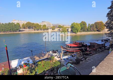 Barges and houseboats near Pont Neuf and the Ile de la Cite on the left bank of the river Seine. Many of these boats are popular tourists rentals. Stock Photo