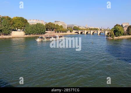 Tourist boat on the river Seine near the right bank, Pont Neuf and the Ile de la Cite. These boats are popular with tourists. Stock Photo