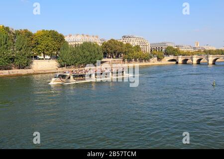 Tourist boat on the river Seine near the right bank, Pont Neuf and the Ile de la Cite. These boats are popular with tourists. Stock Photo